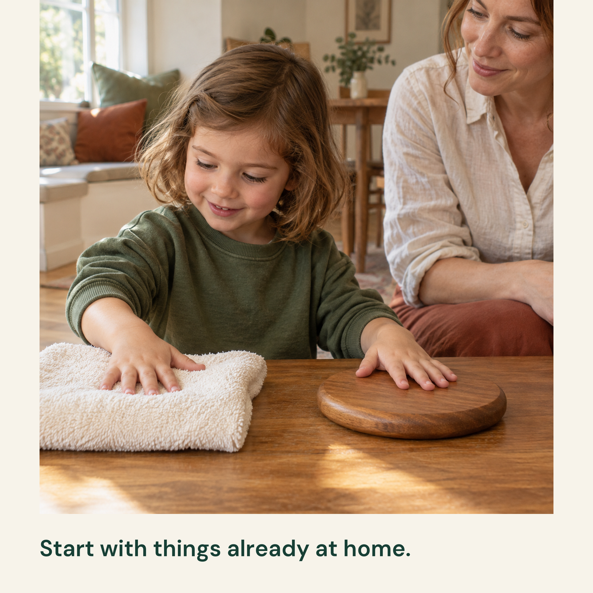 Child explores the contrasting textures of a cloth and wooden disc while mother watches.